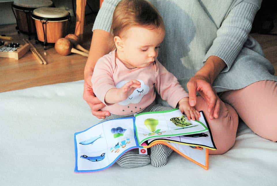 Mutter guckt Bilderbuch mit Kind an
